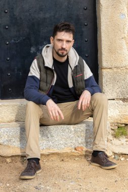 Sokakta poz veren sakallı yakışıklı bir adam. Sıcak giysili şık genç adam. Güneşli bir günde Hipster doğada.