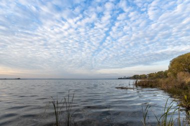 Nero Gölü kıyısında renkli bir gün doğumu. Sabahın erken saatlerinde gölü olan sonbahar manzarası. Ufukta parlak bir ışık çizgisi belirdi, şafak vakti..