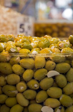 Yığınla zeytin, cam kavanozda, tüketiciler için market tezgahında.