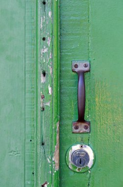 Closeup of lock and knob in closed green antique door on colonial city of Santana do Parnaiba, Sao Paulo state, Brazil