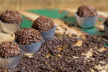 Brigadeiros porsiyonu, geleneksel Brezilya şekeri, kırsal ahşap masaya serpilmiş, granüllü çikolata serpiştirilmiş.