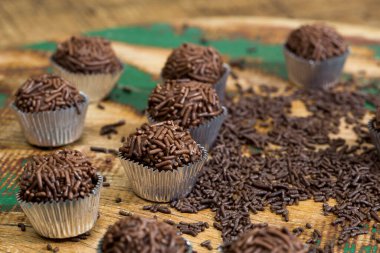 Brigadeiros porsiyonu, geleneksel Brezilya şekeri, kırsal ahşap masaya serpilmiş, granüllü çikolata serpiştirilmiş.