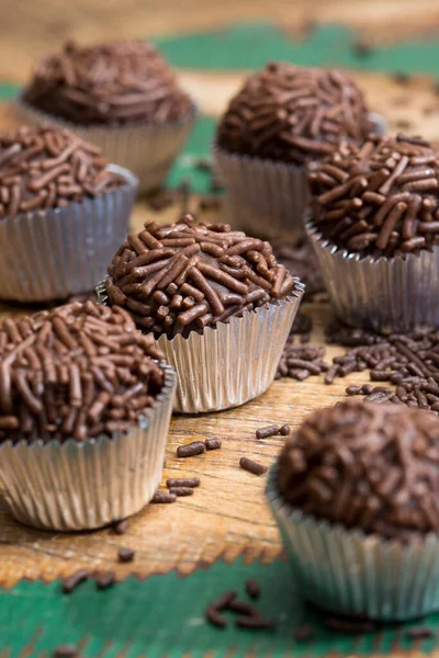 Brigadeiros porsiyonu, geleneksel Brezilya şekeri, kırsal ahşap masaya serpilmiş, granüllü çikolata serpiştirilmiş.