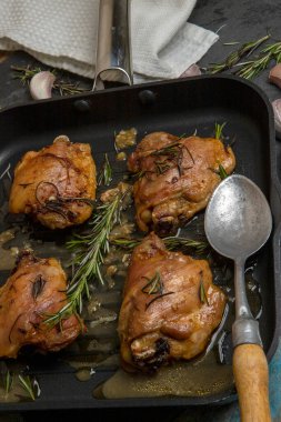 Biberiye ve sarımsaklı kızarmış tavuk budu, siyah kabartma çarşafında.