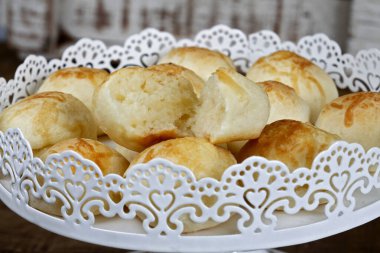 Rustik ahşap arka plan üzerinde beyaz bir şekilde dekore edilmiş tepsisindeki ünlü Brezilyalı peynir ekmek bölümünü