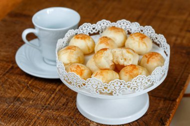 Rustik ahşap arka plan üzerinde beyaz bir şekilde dekore edilmiş tepsisindeki ünlü Brezilyalı peynir ekmek bölümünü