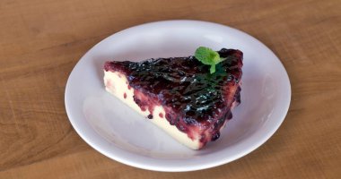 Ahşap masa üzerinde beyaz daire dilim cheesecake reçel ile kaplı