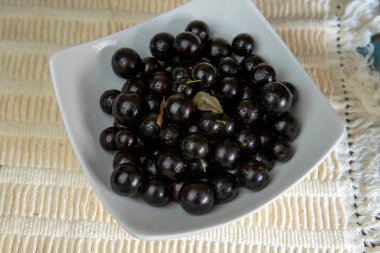 Jaboticaba porsiyonlu, Brezilya üzümlü, beyaz tabakta, masa örtüsünde. Brezilya