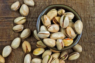 Şam fıstığının bir kısmı kil kasede, ahşap masa üzerinde.