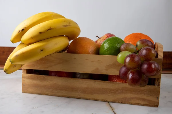 Holzkiste Mit Verschiedenen Früchten Warmen Tönen Auf Weißem Steinhintergrund — Stockfoto