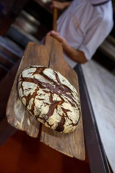 パン屋は木製のへらでオーブンからライ麦パンを削除します ブラジルのサンパウロ州 — ストック写真