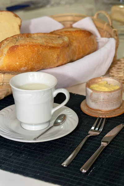 Ekmek, tereyağı ve bir fincan sütle kahvaltı masası. Brezilya