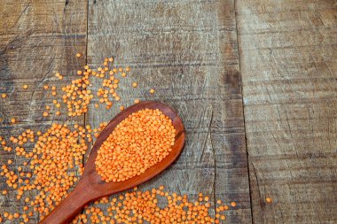 Ahşap tahtada ve metin alanında pembe mercimek ve ahşap kaşık.