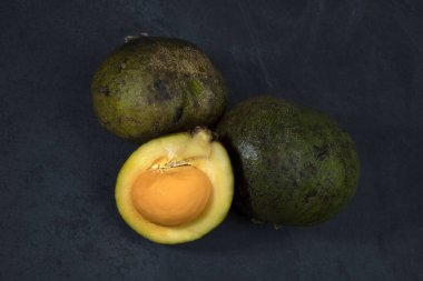 Porsiyon Brezilya meyvesi Pequi, Caryocar brasiliense veya Souari fındığı, bütün ve dilimlenmiş, koyu arkaplanda.