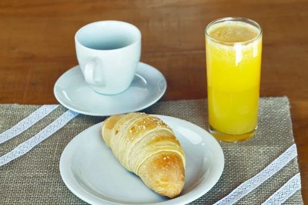 クロワッサンの種類のパン 素朴なジュートテーブルクロス上の料理で 背景にオレンジジュースのカップと — ストック写真
