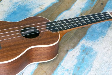 Ukulele, mavi çizgili rustik ahşap tahta üzerinde küçük bir Hawai gitar