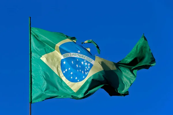 巴西国旗在强风和蓝天下撕裂 — 图库照片