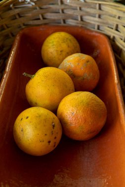 Bambu sepetinin içindeki kil çömlekteki portakal meyvesi.