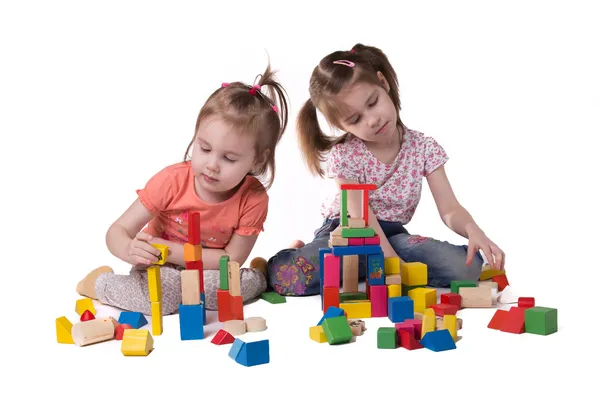 Two girls playing with colorful wooden designer sitting — Stock Photo, Image