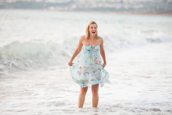Joven hermosa mujer de pie en la playa cerca de las olas Fotos De Stock