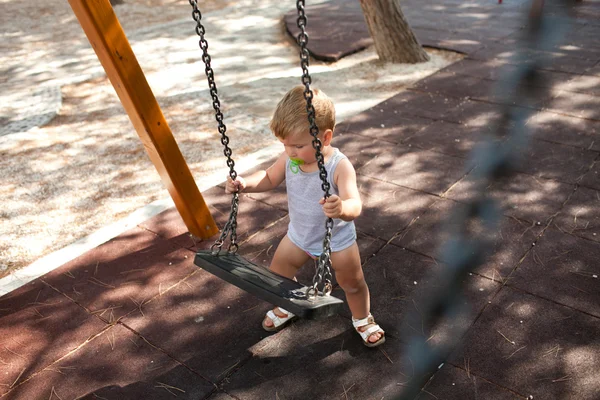 Young child plays on swing in the outdoor playground — Stock Photo, Image