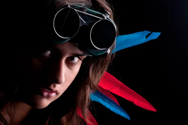 Beautiful young woman posing with goggles and feathers in her hair — Stock Photo, Image