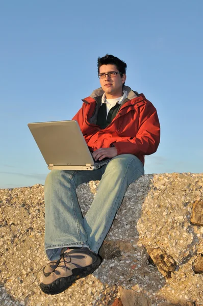 Giovane con computer portatile sulla spiaggia — Foto Stock