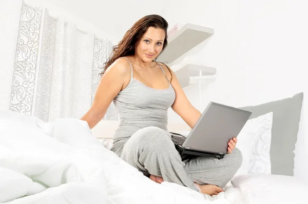 Flicka i pyjamas med laptop — Stockfoto