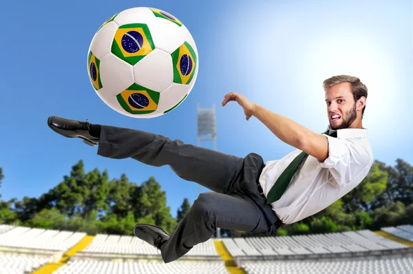 Empresário chutando uma bola de futebol — Fotografia de Stock