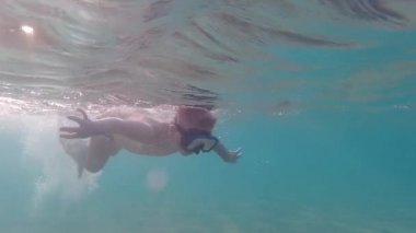 Su altı maskeli bir çocuk yüzmeyi ve dalmayı öğrenir. Çocuk denize dalıyor..