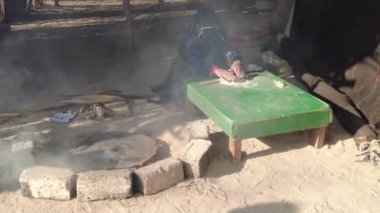 Hurghada, Mısır - Ocak 2022: Peçeli bir kadın ateşin üzerinde ekmek hazırlıyor. Bedevi hayatı.