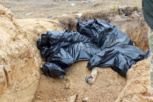 Bucha, Kyiv bölgesi, Ukrayna - Nisan 2022: Rusya ve Ukrayna arasındaki savaş. Rus ordusunun askerleri tarafından vurulan sivillerin toplu mezarı, kilisenin topraklarında gömülü.