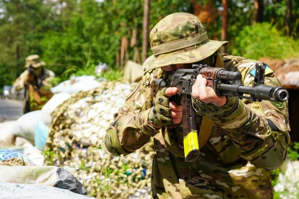 Poltava-Kharkiv region, Ukraine - August 2022: Ukrainian military is on duty at the checkpoint. Soldier of the volunteer formation of the territorial community on combat duty. Weapon in the hands of a military soldier.