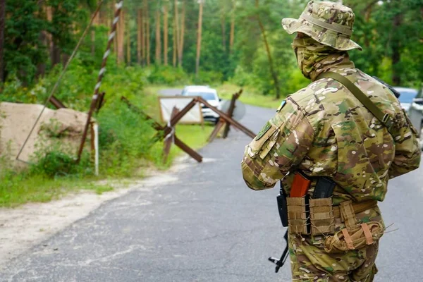 Poltava-Kharkiv region, Ukraine - August 2022: Ukrainian military is on duty at the checkpoint. Soldier of the volunteer formation of the territorial community on combat duty. Weapon in the hands of a military soldier.