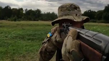 Poltava-Kharkiv region, Ukraine - August 2022: Ukrainian territorial defense fighter shoots from American M14 rifle. M14 rifle in the hands of a Ukrainian soldier. Shell casings are poured from firearms during firing.
