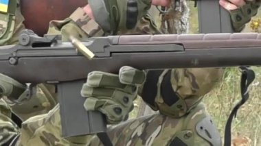 Poltava-Kharkiv region, Ukraine - August 2022: Ukrainian territorial defense fighter shoots from American M14 rifle. M14 rifle in the hands of a Ukrainian soldier. Shell casings are poured from firearms during firing.