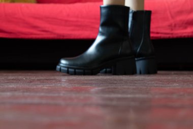 Yüksek siyah çizmeli kız evdeki eski kirli zeminde, kadın ayakkabıları, yerde ayaklar, ahşap zeminde ayakkabılar