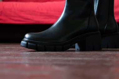 Yüksek siyah çizmeli kız evdeki eski kirli zeminde, kadın ayakkabıları, yerde ayaklar, ahşap zeminde ayakkabılar