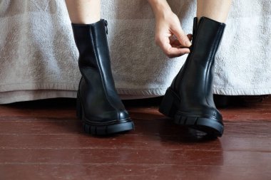 Yüksek siyah çizmeli kız evdeki eski kirli zeminde, kadın ayakkabıları, yerde ayaklar, ahşap zeminde ayakkabılar