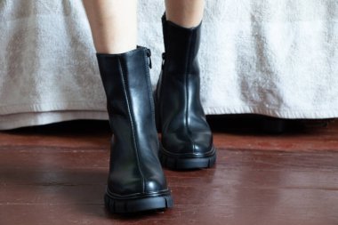 Yüksek siyah çizmeli kız evdeki eski kirli zeminde, kadın ayakkabıları, yerde ayaklar, ahşap zeminde ayakkabılar