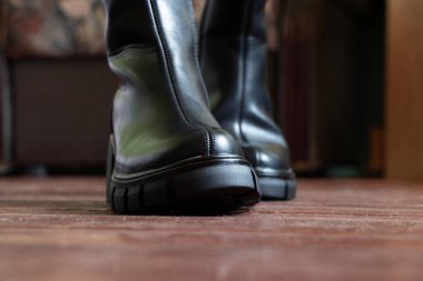 Yüksek siyah çizmeli kız evdeki eski kirli zeminde, kadın ayakkabıları, yerde ayaklar, ahşap zeminde ayakkabılar