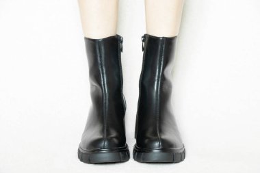 Beyaz arka planda yüksek siyah çizmeli bir kız, kadın ayakkabıları, yerde ayakları, beyaz arka planda kadın ayakları.