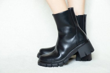 Beyaz arka planda yüksek siyah çizmeli bir kız, kadın ayakkabıları, yerde ayakları, beyaz arka planda kadın ayakları.