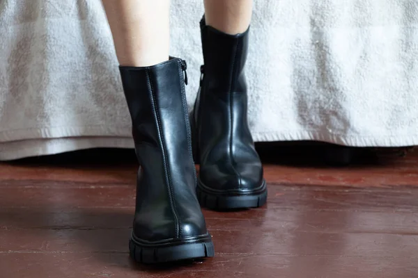 Yüksek siyah çizmeli kız evdeki eski kirli zeminde, kadın ayakkabıları, yerde ayaklar, ahşap zeminde ayakkabılar