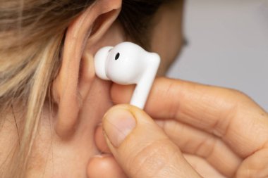Kablosuz TWS beyaz kulaklıklar bir kızın kulaklığında, kulaklıkla müzik dinliyor, kablosuz kulaklıklar