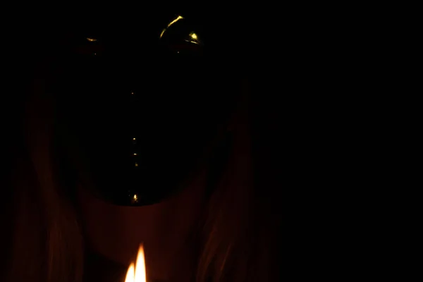 face of a girl in a carnival mask in the dark goats flame candles, a man in a mask, carnival mask