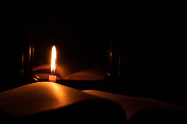 İncil kitabı ve aynanın yanında yanan bir mum taburedeki karanlıkta, dua, din.