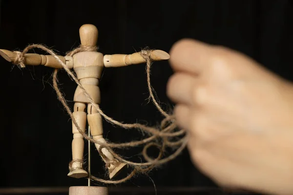 绑在男人手上的绳子上的木头人 操纵人民和奴隶制 自由意志 对人民的权力 — 图库照片