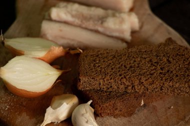 Bir parça pastırma soğanlı sarımsaklı ekmek ahşap bir masada, ev usulü domuz pastırmalı öğle yemeği.