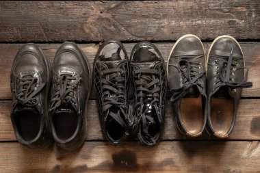 Bir sürü kadın ayakkabısı ve tahta zeminde eski spor ayakkabılar, kadın ayakkabıları, siyah spor ayakkabılar.